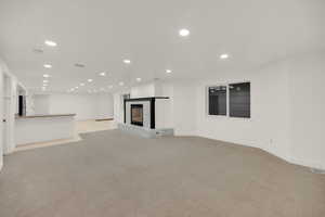 Unfurnished living room with recessed lighting, light carpet, and a high end fireplace