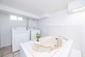 Full bathroom with a garden tub, light tile patterned floors, and washer and dryer