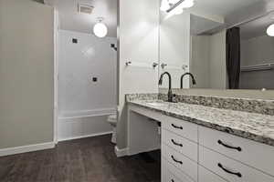 Full bathroom featuring vanity, dark wood-type flooring, and washtub / shower combination