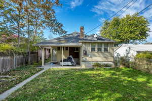 Rear view of property featuring a fenced backyard, a patio, and a chimney