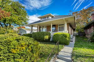 Bungalow featuring roof with shingles, a porch, brick siding, and a front yard