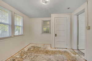 Empty room with a textured ceiling and baseboards