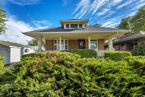 View of front of home featuring brick siding, a shingled roof, and a porch