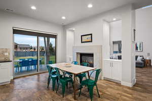 Dining space featuring a glass covered fireplace, recessed lighting, and dark wood-style flooring