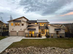 Contemporary house featuring stone siding, a metal roof, driveway, and a garage