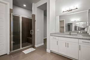 Bathroom featuring vanity, a shower stall, and light tile patterned floors