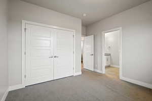 Unfurnished bedroom with light carpet, a closet, and ensuite bathroom
