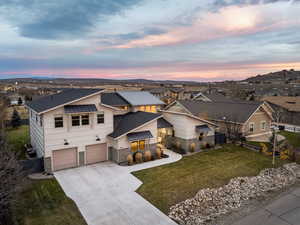 View of front of home with concrete driveway, stone siding, an attached garage, and a shingled roof