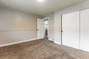 Unfurnished bedroom with a textured ceiling, carpet flooring, and a closet