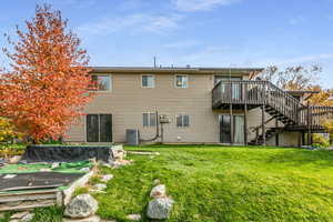 Back of house with stairway, a wooden deck, and a yard