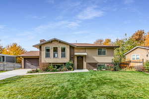 Bi-level home featuring concrete driveway, stucco siding, a chimney, and brick siding
