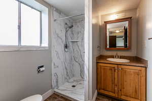 Full bathroom with vanity, a marble finish shower, and a textured ceiling
