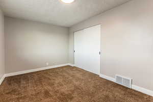 Unfurnished bedroom featuring a textured ceiling, a closet, and carpet flooring