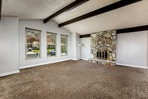 Unfurnished living room with a textured ceiling, a fireplace, and carpet
