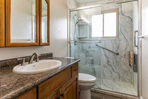 Bathroom featuring vanity and a marble finish shower