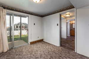Carpeted spare room featuring a textured ceiling