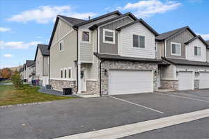 Craftsman inspired home featuring board and batten siding, stone siding, a residential view, driveway, and an attached garage