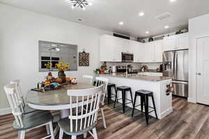 Kitchen with dark stone countertops, appliances with stainless steel finishes, a peninsula, white cabinets, and dark wood finished floors