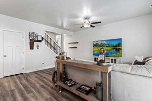 Living area with wood finished floors, stairs, and a ceiling fan
