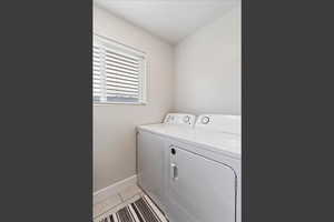 Washroom with light tile patterned floors and independent washer and dryer