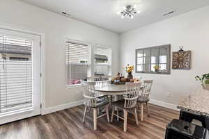 Dining space with dark wood-style floors and a chandelier