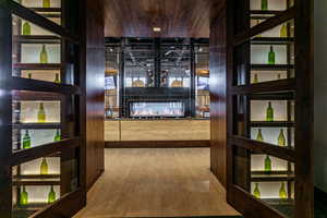 Wine room featuring a multi sided fireplace and wood finished floors