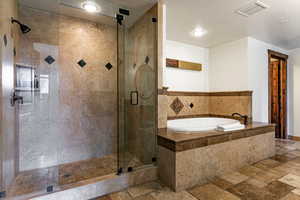 Primary Full bath featuring stone tile floors, a bath, a stall shower, and a textured ceiling