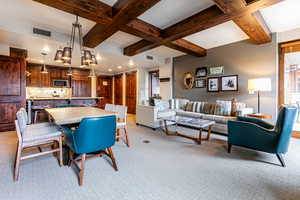 Dining room with beamed ceiling, coffered ceiling, and light carpet