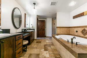 Primary Full bathroom with a bath, double vanity, stone tile flooring, a textured ceiling, and a stall shower