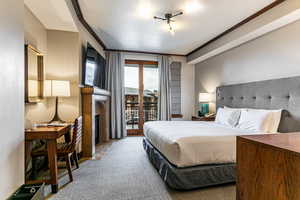 Bedroom 2 with carpet flooring, a fireplace with flush hearth, access to outside, and ornamental molding