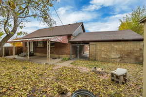 Back of property with a patio, brick siding, and roof with shingles