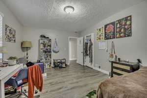 Bedroom with light wood-type flooring and a textured ceiling