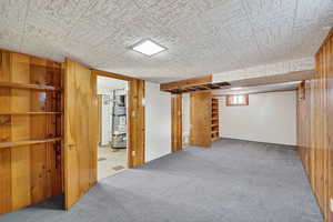 Below grade area with wood walls, carpet floors, and strapped water heater