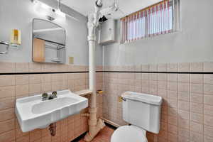 Half bathroom with tile walls and a wainscoted wall