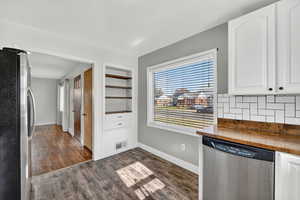 Kitchen with appliances with stainless steel finishes, wood counters, white cabinetry, and dark wood-style floors