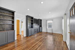 Unfurnished living room with dark wood-type flooring, recessed lighting, a textured ceiling, and built in features