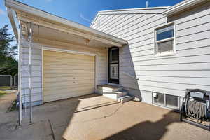 Entrance to property featuring a garage, a patio area, and driveway