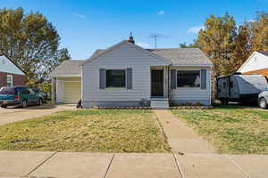 Bungalow-style home featuring a front lawn, roof with shingles, entry steps, and an attached garage