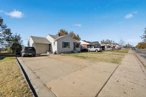 View of front facade with driveway, a front yard, a chimney, and a garage