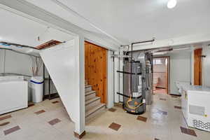 Finished basement featuring washer / clothes dryer, light flooring, white fridge, water heater, and a water softener