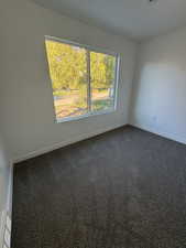 Unfurnished room with baseboards and dark colored carpet