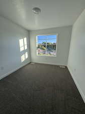 Unfurnished room featuring dark carpet and a textured ceiling