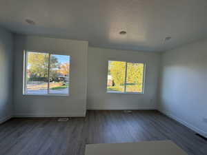 Unfurnished room featuring dark wood finished floors and a textured ceiling