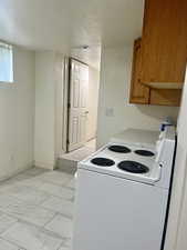 Kitchen featuring white electric range, a textured ceiling, light countertops, and brown cabinets