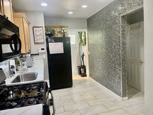 Kitchen with black appliances, recessed lighting, and light brown cabinetry