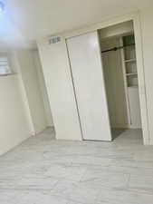 Unfurnished bedroom featuring a closet and light marble finish flooring