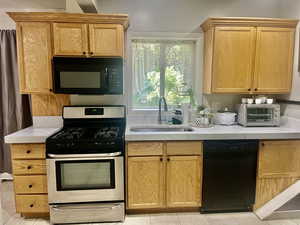 Kitchen with black appliances and light tile patterned flooring