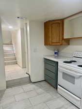 Kitchen featuring white range with electric stovetop, light countertops, a textured ceiling, and brown cabinets