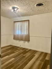 Empty room with wood finished floors and a textured ceiling