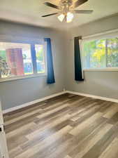 Spare room with healthy amount of natural light, wood finished floors, and ceiling fan